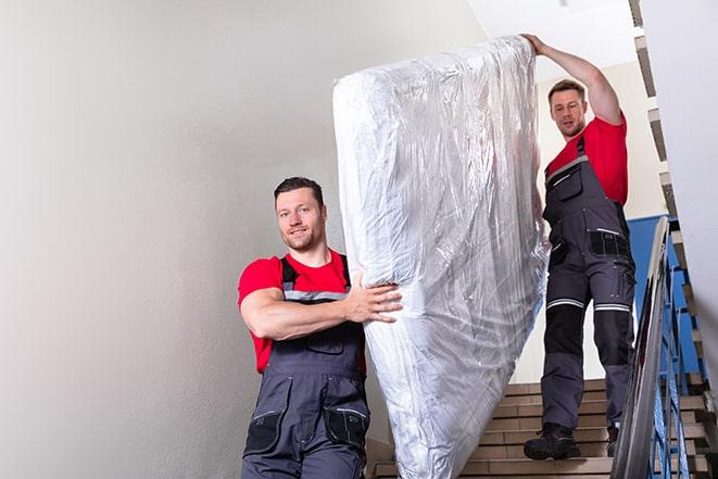 workers maneuvering a box spring through a narrow hallway in Babson Park